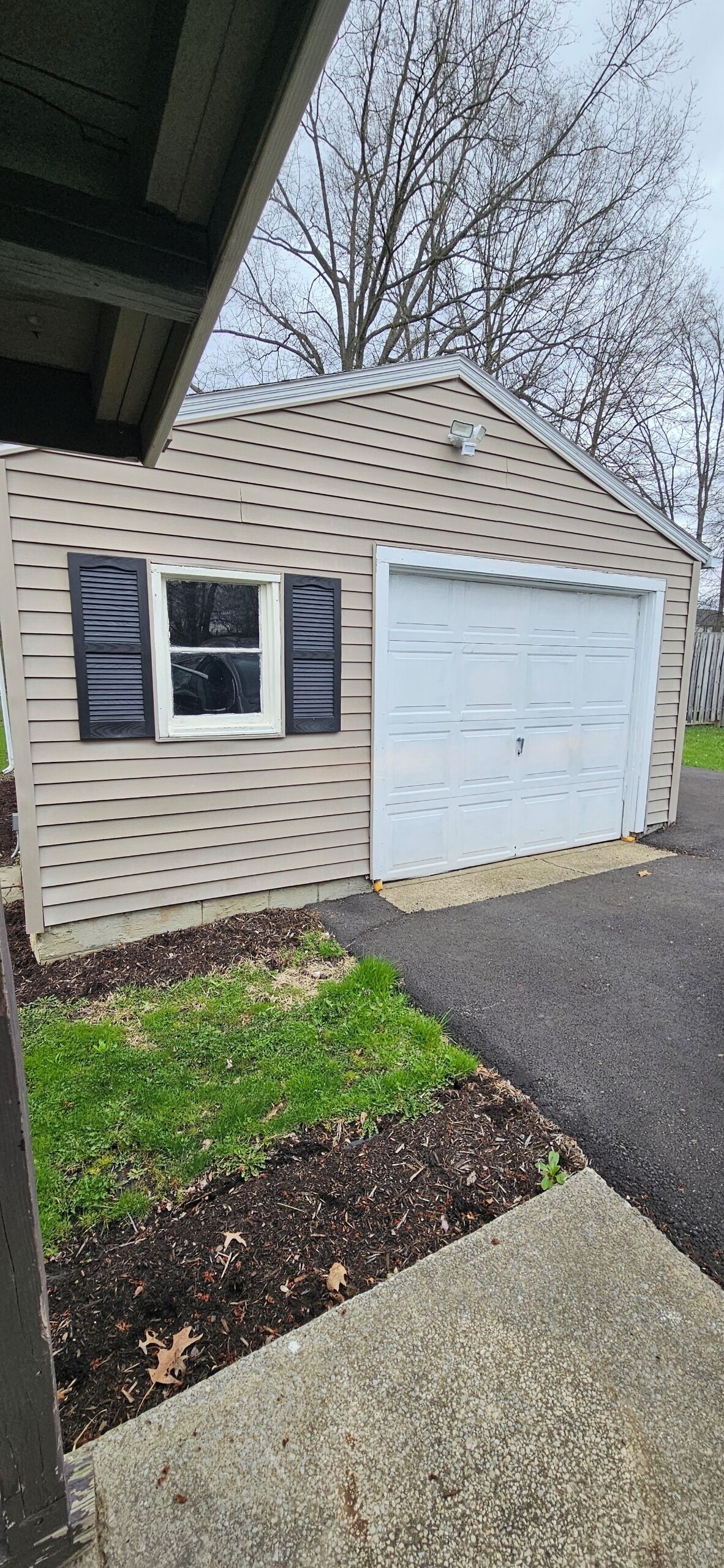 Ein eingeschossiges Haus mit Garage, kleinem Fenster mit Fensterläden und gepflegtem Rasen.