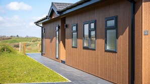 A modern building with a wooden facade and large windows. - Countryside Lodge Retreat on Golf Course (Blackawton)