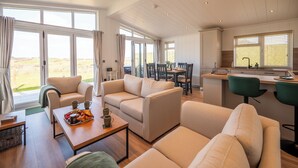 A spacious living area with a dining table, sofas, and a kitchen area with a window. - Countryside Lodge Retreat on Golf Course (Blackawton)