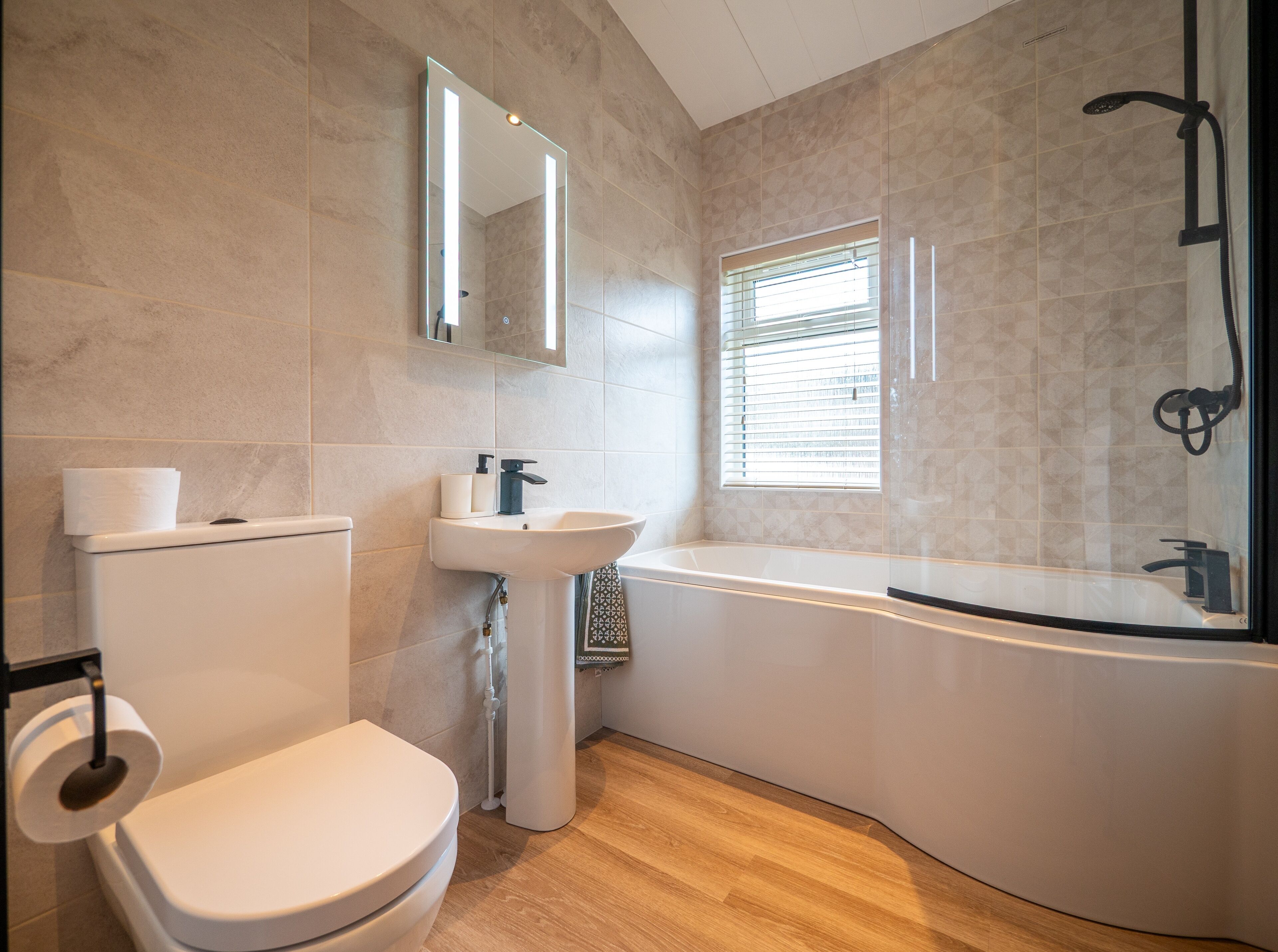 A modern bathroom with a toilet, sink, and bathtub.