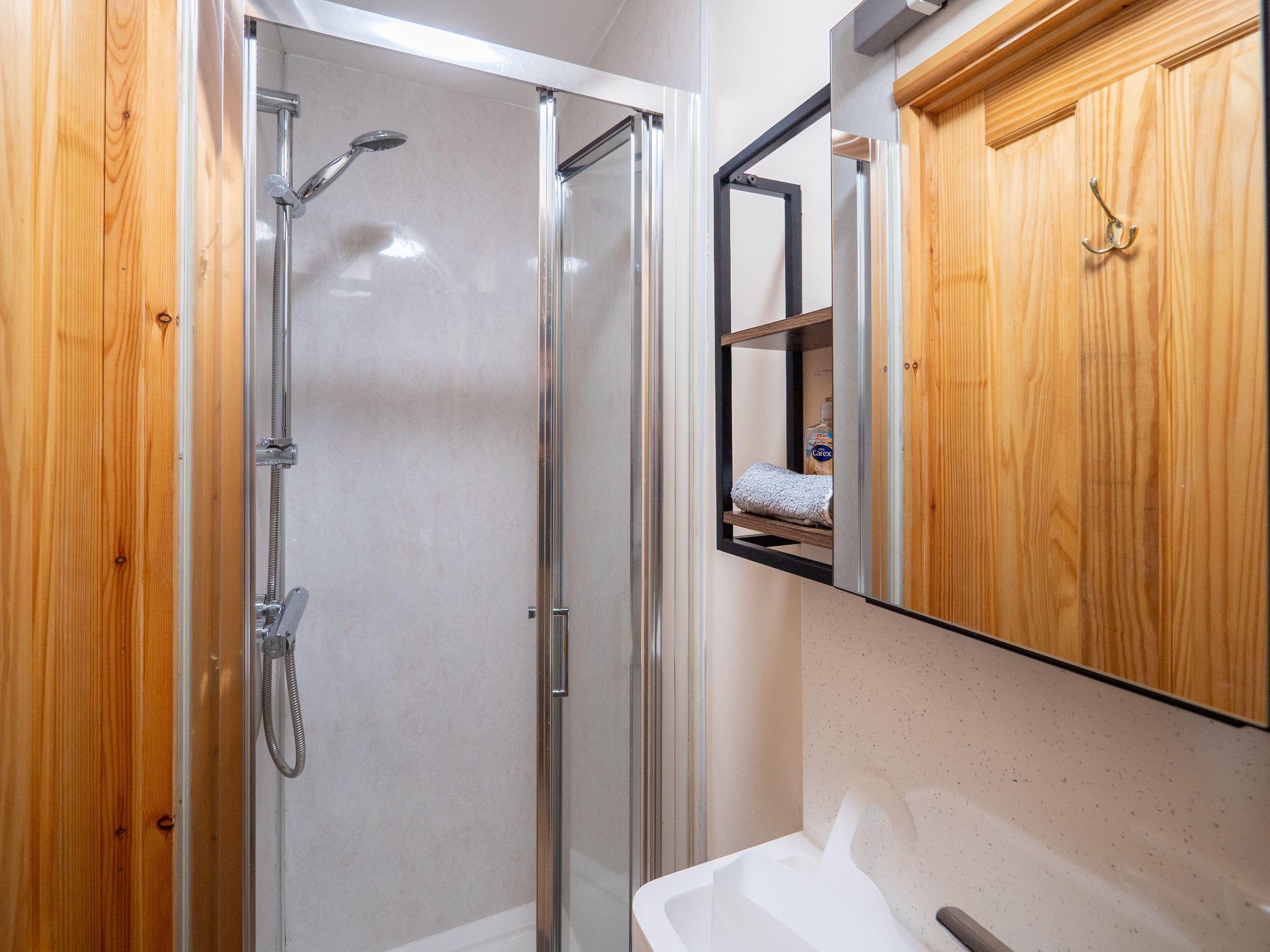 A modern bathroom with a glass-enclosed shower, a wooden vanity, and a mirror cabinet.