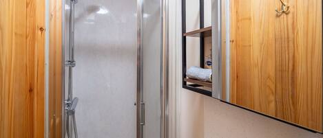 A modern bathroom with a glass-enclosed shower, a wooden vanity, and a mirror cabinet.