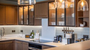 A modern kitchen with wooden cabinets, a built-in oven, a sink, and a coffee maker. - Stylish Waterfront Home With River Dart Views (Dartmouth)