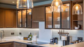 A modern kitchen with wooden cabinets, a built-in oven, a sink, and a coffee maker.