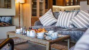 A cozy living room with a sofa, striped pillows, a coffee table with breakfast items, and a lamp. - Stylish Waterfront Home With River Dart Views (Dartmouth)