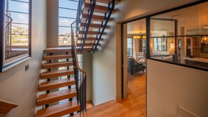 A modern interior with a wooden staircase leading to a dining area. - Stylish Waterfront Home With River Dart Views (Dartmouth)