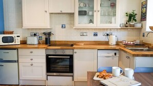 A modern kitchen with white cabinets, a built-in oven, a microwave, and a dishwasher.