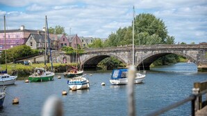 A stone bridge over a river with boats docked nearby.