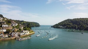 A coastal town with a marina filled with boats, surrounded by hills and residential buildings.