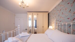 Ein Schlafzimmer mit Bett, Nachttisch, Kommode und Spiegel.
