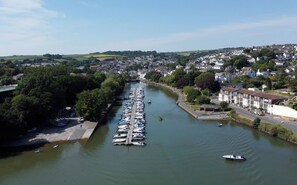 A river with boats docked along the banks, surrounded by residential buildings and greenery. - Bright Bungalow Near Town & Estuary with parking (Kingsbridge)