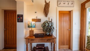 A wooden table with a lamp, a wall clock, and a framed map. - Farmhouse with Garden & Countryside Views (Totnes)