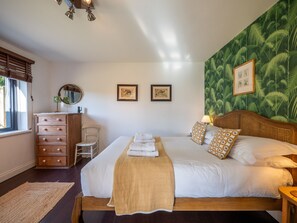 A bedroom with a bed, dresser, chair, and a window with blinds. - Farmhouse with Garden & Countryside Views (Totnes)