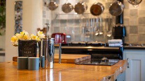 A kitchen counter with a coffee grinder, a thermos, and a vase with flowers. - Farmhouse with Garden & Countryside Views (Totnes)