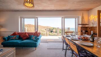 Un salon chaleureux avec un canapé de couleur turquoise, une table à manger en bois et une vue sur les collines.