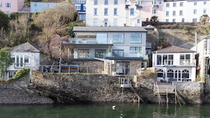 Ein Küstengebäude mit einer Steinmauern, einem Balkon und Blick aufs Meer.