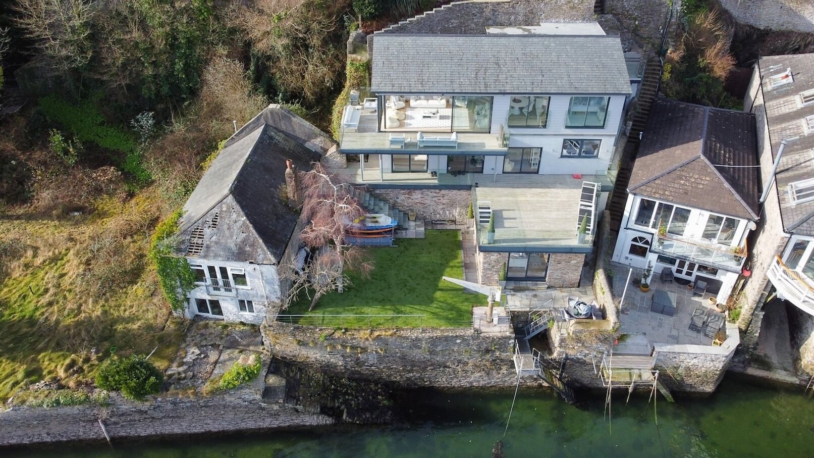 Une maison moderne dotée d’un grand patio, d’un petit jardin et d’un élément décoratif aquatique.