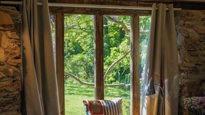 A room with a large window, a stack of books, and a lamp on a windowsill. - Escape to an Idyllic Countryside Couple's Retreat (Totnes)