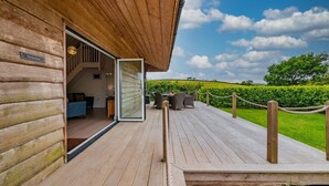 A wooden deck with a glass door leading to an interior space, a sign reading "The Hen House," and a view of a green landscape. - Relaxed Devon Stay Close to fabulous Beaches (Slapton)