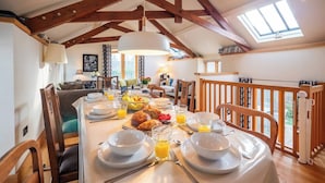 Un comedor con techo alto, vigas de madera y una mesa preparada para el desayuno.