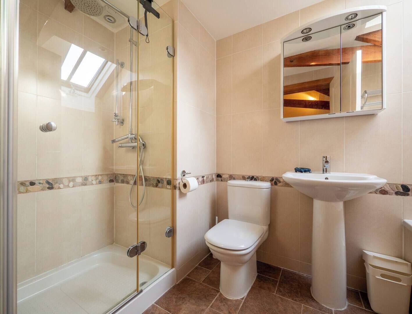 A bathroom with a glass-enclosed shower, a toilet, and a sink.