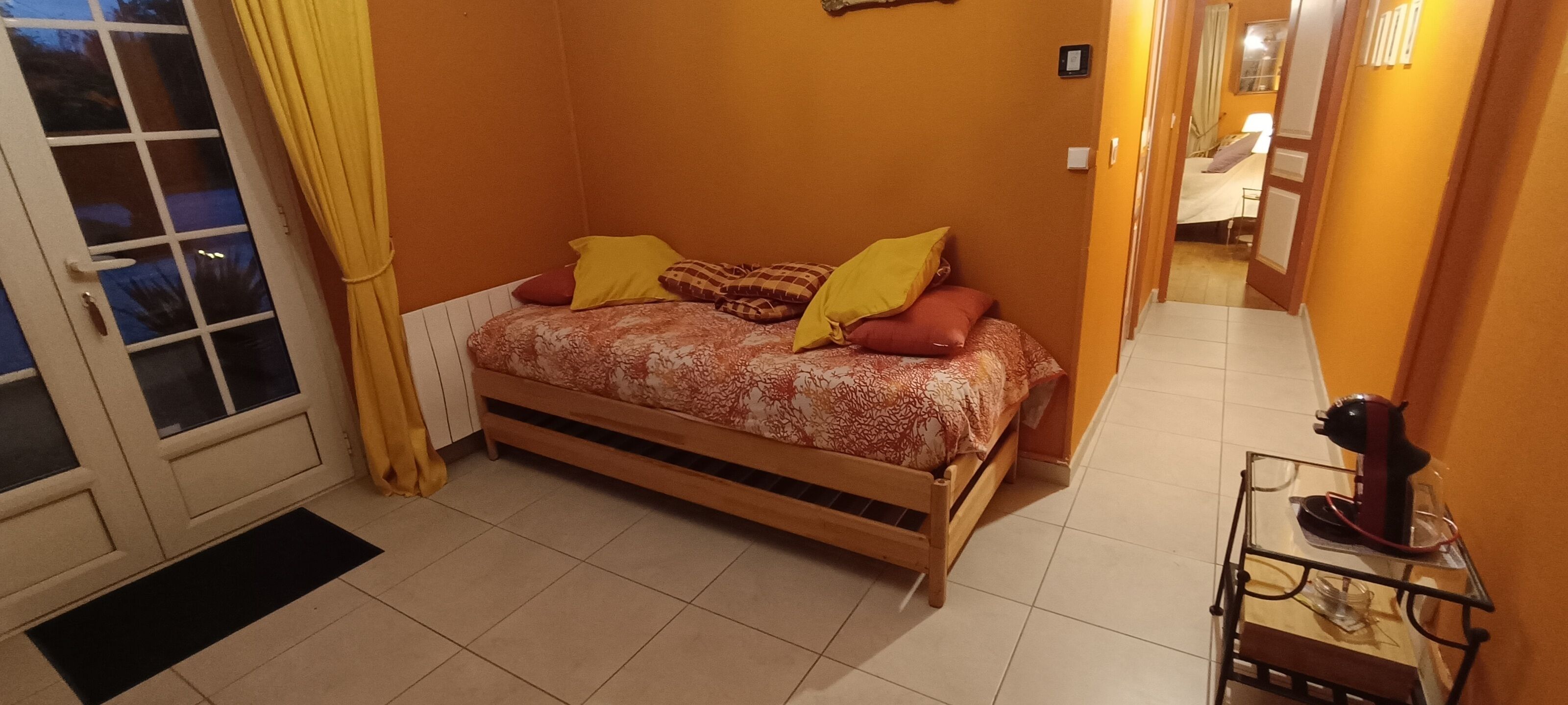 Un dormitorio con cama, mesita de noche y una puerta con cortina.