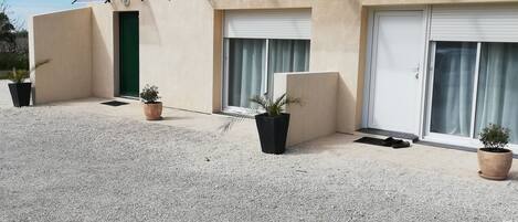A building with a tiled roof, a green door, and a gravel driveway.
