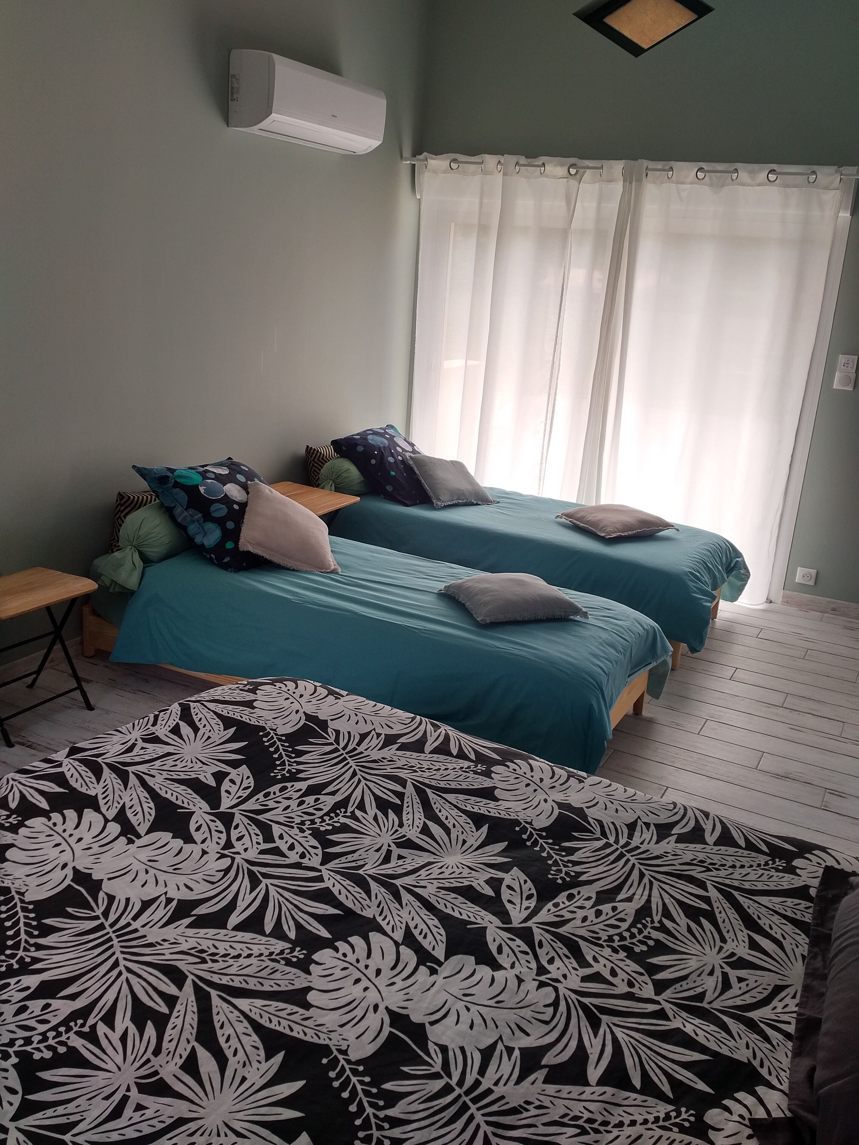 A room with two beds, a desk, and a window with curtains.