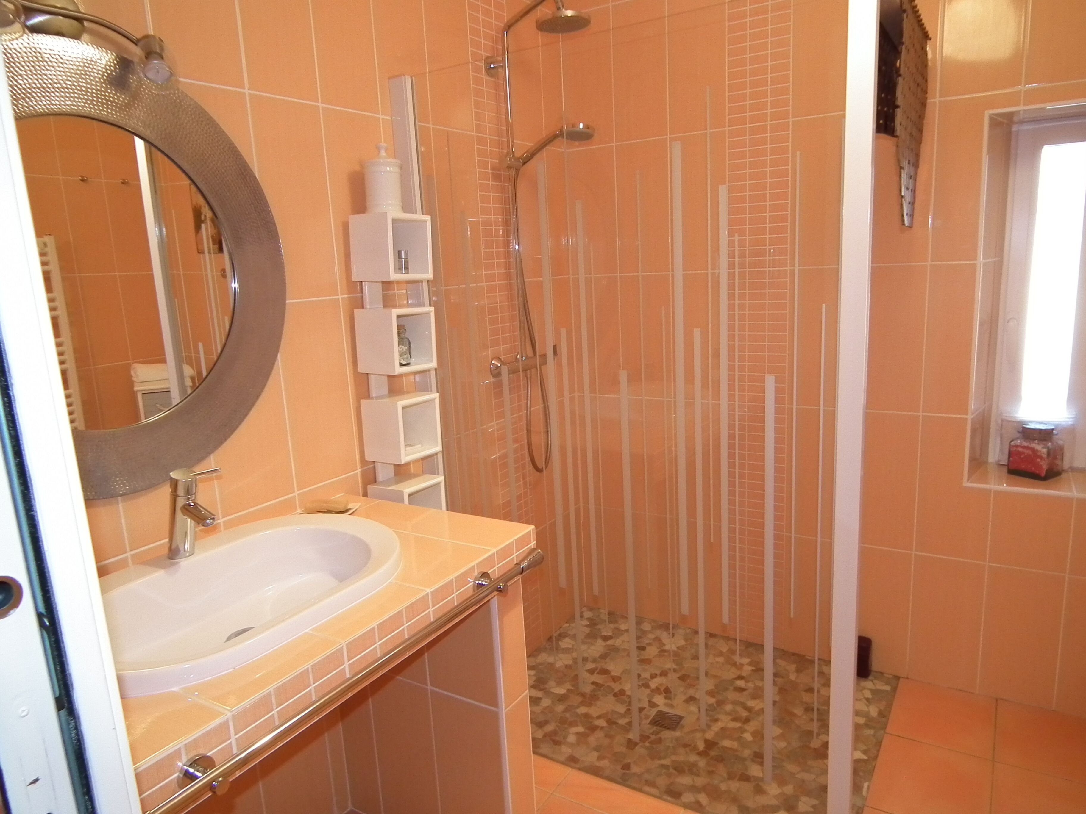 A bathroom with a sink, mirror, shower, and tiled walls.