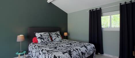 A bedroom with a bed, a nightstand, a lamp, and a window with curtains.