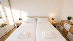 A double bed with white linens, two bedside tables with lamps, a wooden cabinet, and a potted plant. - Nice vacation apartment near Pückler Park /pet friendly/ sauna in the house (Bad Muskau)