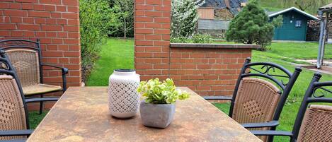 Eine Terrasse mit Tisch und Stühlen, einem Blumentopf und einem weißen Zierelement.