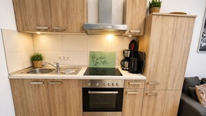 A modern kitchen with wooden cabinets, a stainless steel stove, a sink, and a coffee maker. - Nice vacation apartment near Pückler Park /pet friendly/ sauna in the house (Bad Muskau)