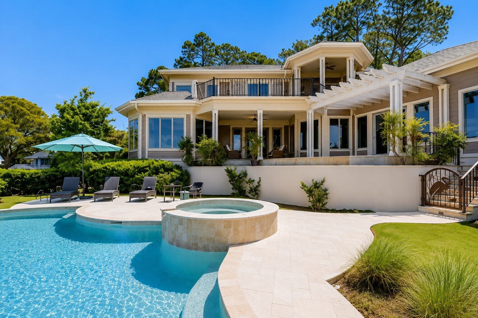 Une maison à deux étages avec une piscine, un espace salon extérieur et une terrasse couverte.