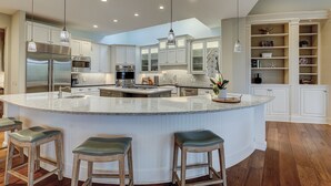 A spacious kitchen with a large island, stainless steel appliances, and pendant lighting. - 28 Oyster Landing -  A Magnificent Marsh View in Sea Pines! (Hilton Head Island)