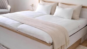 A bed with white bedding and a beige throw blanket, a bedside lamp, and a chair in a room with a wooden headboard. - Quiet vacation apartment with two bedrooms Bad Muskau - Fürst Pückler Park (Bad Muskau)