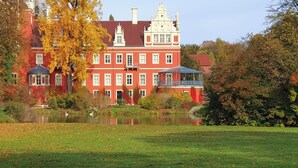 A large red building with a reflective pond in front, surrounded by trees and greenery. - Quiet vacation apartment with two bedrooms Bad Muskau - Fürst Pückler Park (Bad Muskau)
