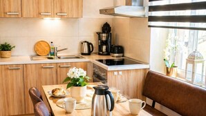 A kitchen with a wooden table, coffee maker, and a window with plants. - Quiet vacation apartment with two bedrooms Bad Muskau - Fürst Pückler Park (Bad Muskau)