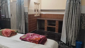 Une chambre d’hôtel comprenant un lit, un petit coin salon, une salle de bain avec douche et un mur carrelé.
