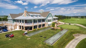 A large building with multiple levels, a covered patio, and a well-maintained lawn with a putting green. - Amenity filled Peninsula!  24242 Canoe (Millsboro)