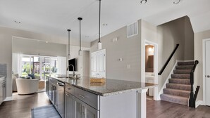 A modern kitchen with a central island, stainless steel appliances, and pendant lighting. - Amenity filled Peninsula!  24242 Canoe (Millsboro)
