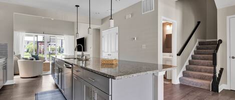 A modern kitchen with a central island, stainless steel appliances, and pendant lighting.