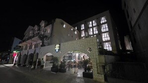 A building with an arched entrance, a sign reading "Hotel", and outdoor seating. - Hotel Lobo (Budva)