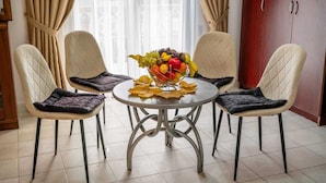 A dining area with a round table, four chairs, and a fruit bowl on the table. - Hotel Lobo (Budva)