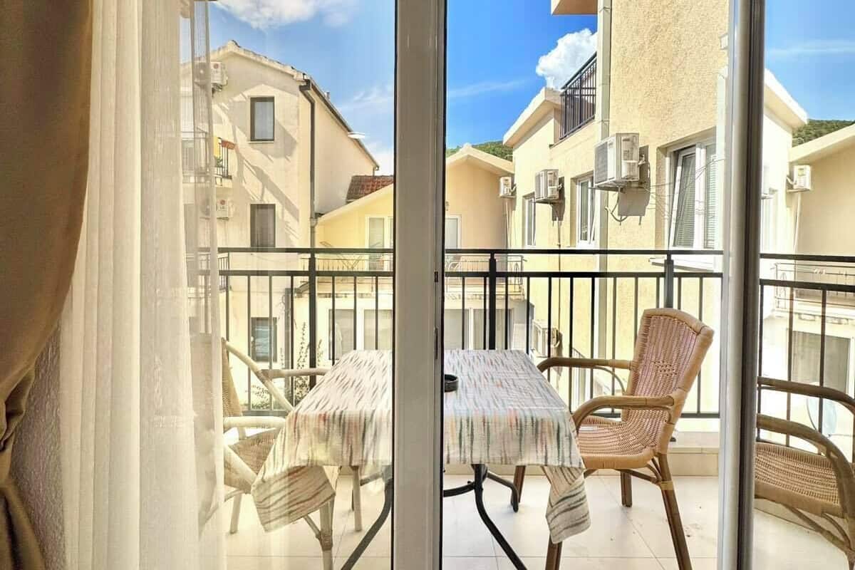 Un balcón con mesa y sillas, con vista a una zona residencial.