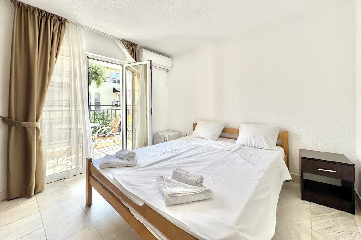 Una habitación de hotel con una cama, una mesita de noche y vistas al balcón exterior.