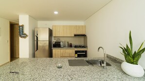 A modern kitchen with granite countertops, stainless steel appliances, wooden cabinets, and a potted plant. - Modern apartment near the sea (Cartagena de Indias)