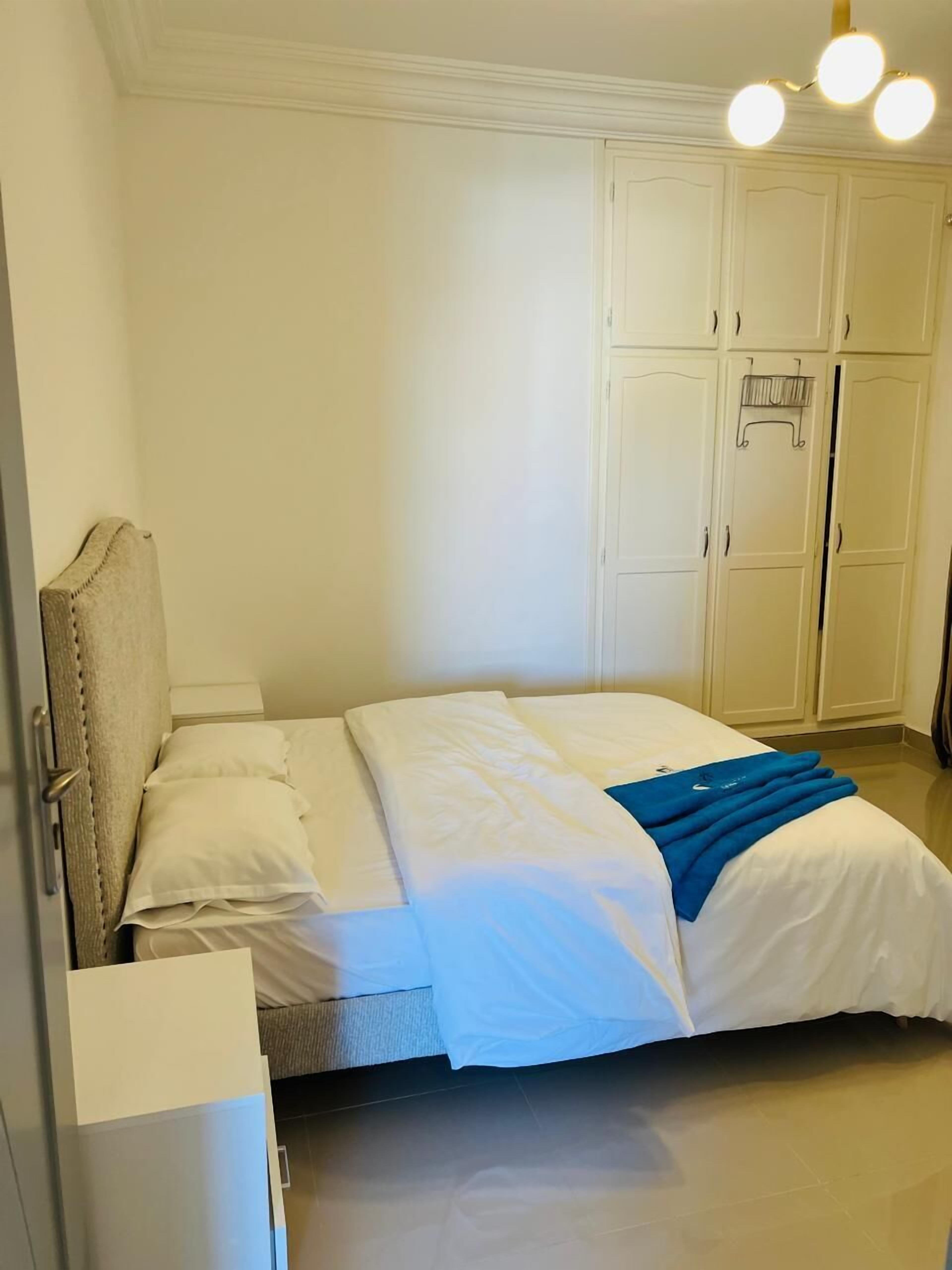 A bedroom with a bed, a wardrobe, and a nightstand.