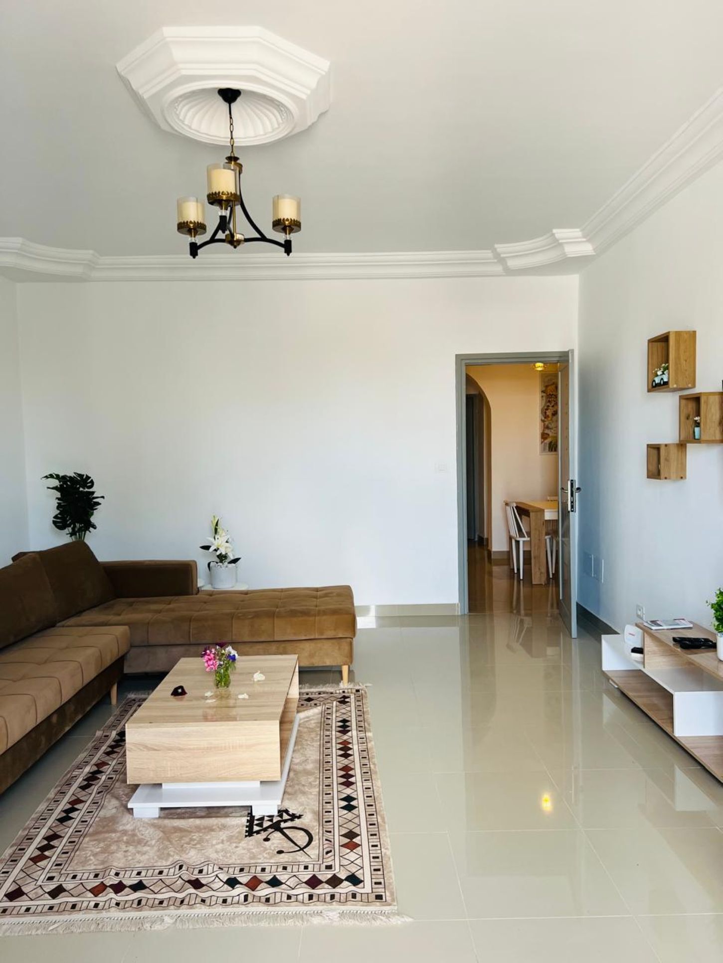 Een moderne woonkamer met een hoekbank, een houten salontafel en een vloerkleed met dessin.