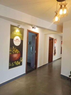 A hotel corridor with a poster advertising Cardamom Maryland, a wooden door, and a hanging light fixture.